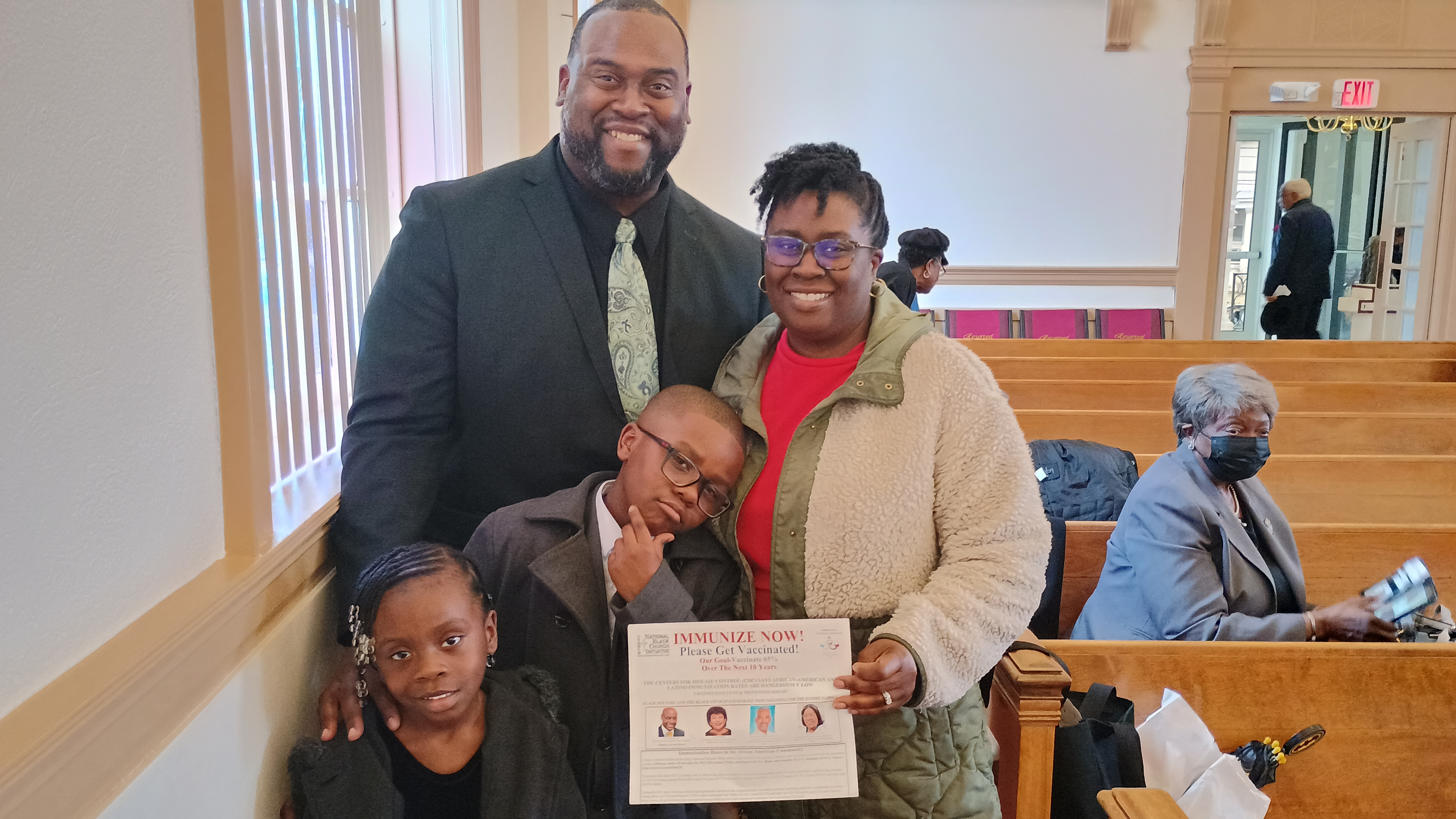 Family at church with their copy of 'Immunize Now'