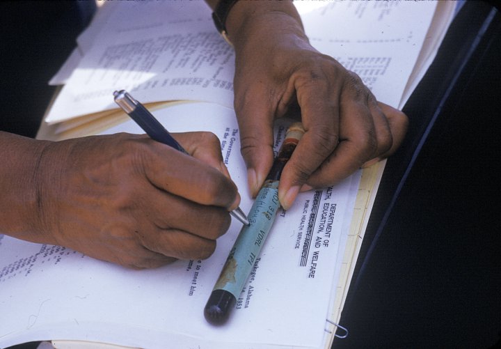 In this 1950's photo released by the National Archives, a nurse writes on a vial of blood taken from a participant in a syphilis study in Tuskegee, Ala.